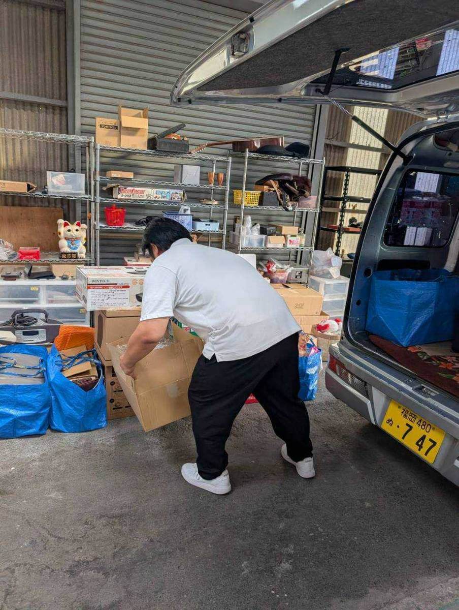 かいとり隊スタッフが買取品を持ち上げて車両へ積み込む作業風景